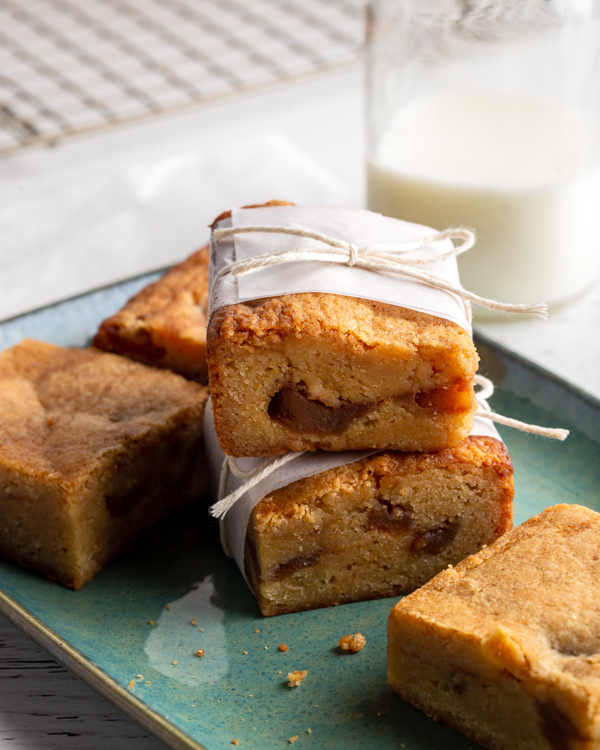 Apple blondies on a serving platter, some wrapped with parchment paper