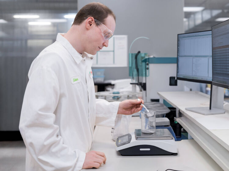 Worker in safety gear conducting sample testing at a laboratory workstation