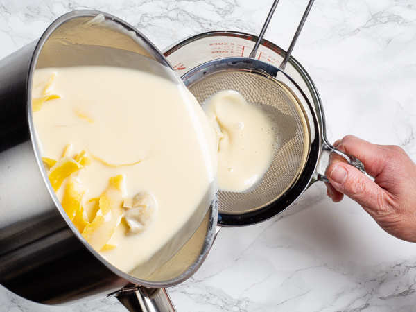 Straining solids from lemon and cream mixture through a sieve