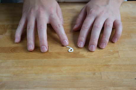 8. Now it is time to make the handle. To do this roll a very thin line of fondant into a log and cut about an inch. Form the log into a €œ9€ shape dip in a little bit of water and attach to the side of the teapot.