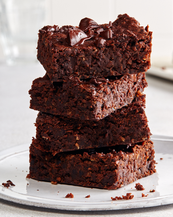 A stack of four vegan chocolate brownies on a white plate