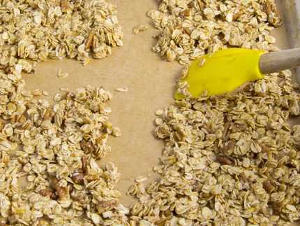 Spreading wet granola mixture on a parchment-lined baking sheet