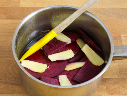 Slices of beet and ginger in a saucepan with water and a spatula