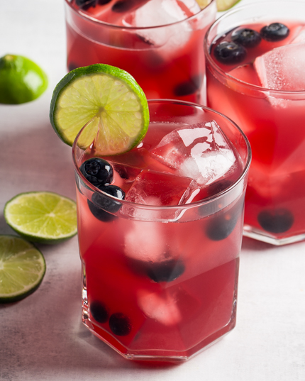 Three glasses of Blueberry Beer Cocktail garnished with blueberries and lime