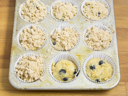 Muffin batter in a muffin tin topped with maple crumble