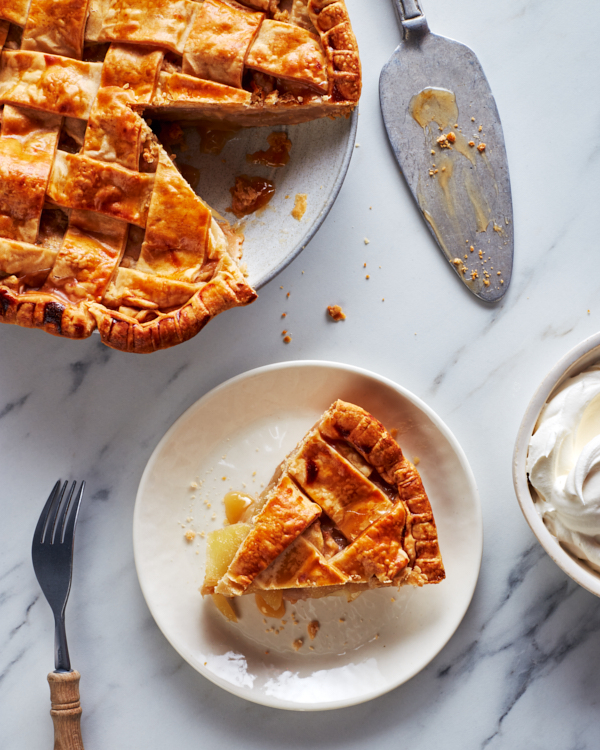 Lattice-topped apple pie on a platter with one slice cut and served on a plate