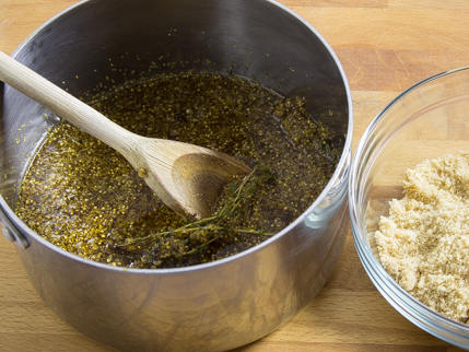 Cooking pot full of thyme, water, and elderflowers, with a wooden stirring spoon
