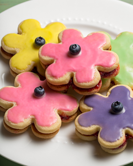 A pile of glazed flower shaped sandwich cookies on a plate