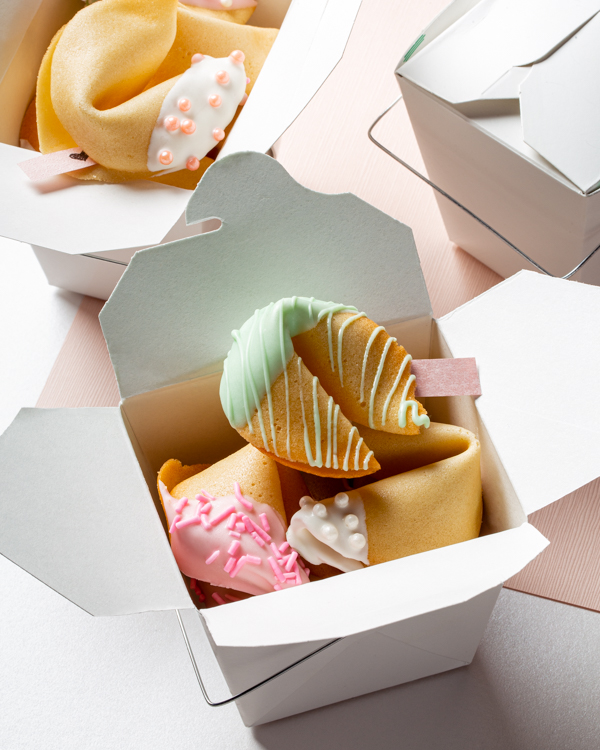 Fortune cookies dipped in icing and decorated with sprinkles in Chinese food boxes