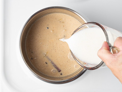 Pouring remaining buttermilk into a pot of buttermilk, heavy cream, and spices