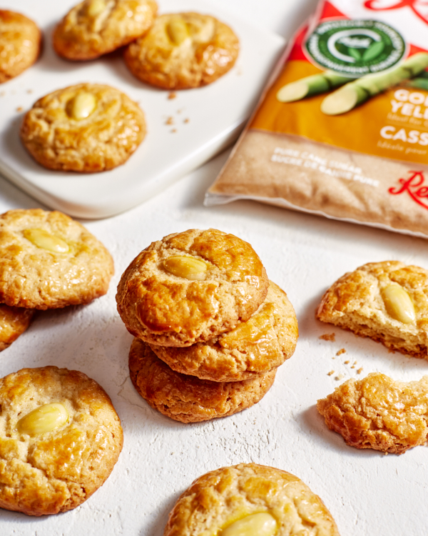 Piles of golden almond cookies with a bag of Redpath Golden Brown Sugar