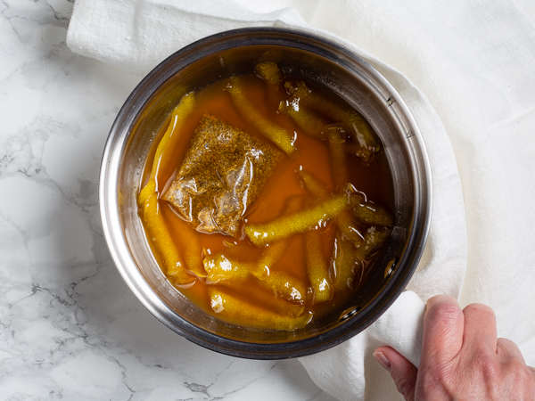 Lemon and sugar syrup in a pot with a tea bag and lemon zest