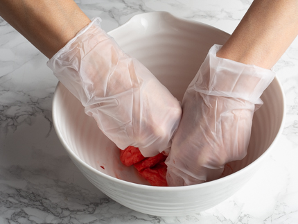 Kneading red food colouring and marzipan using gloves