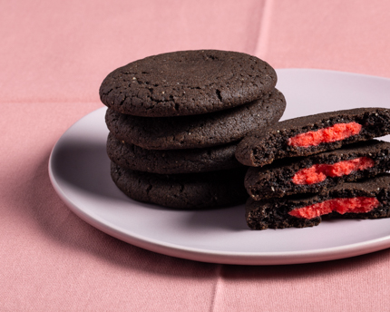 Stacks of dark chocolate cookies stuffed with red marzipan