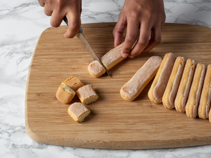 Cutting ladyfingers on a cutting board into small pieces