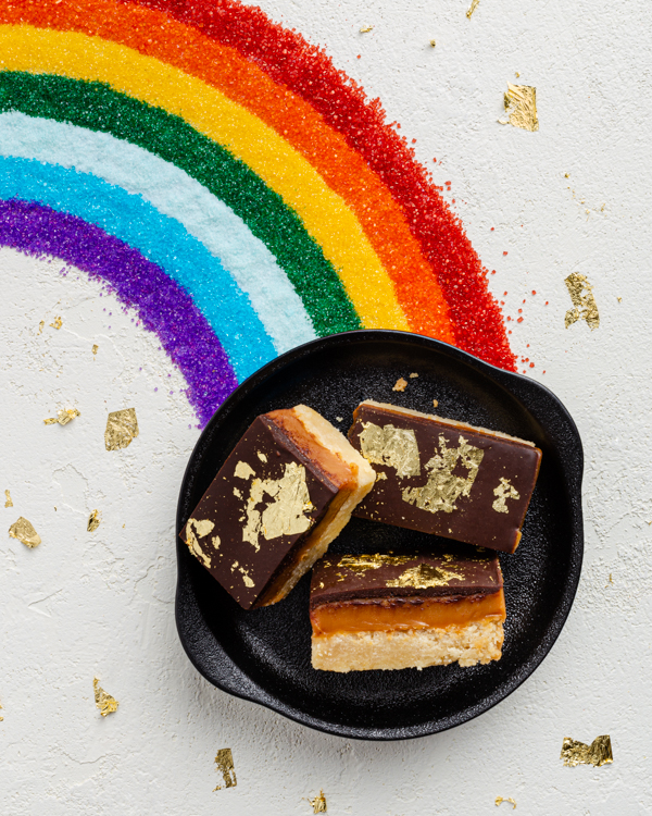 3 millionaire shortbread bars in a skillet at the end of a rainbow