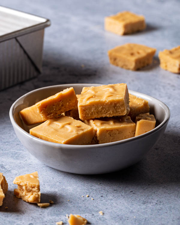 Squares of brown sugar fudge in a bowl on a counter