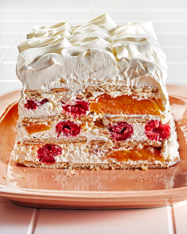 Peach melba icebox cake revealing layers of cookies, cream, peaches, and raspberries