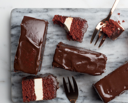 Chocolate dipped red velvet cake bars with forks on a cutting board