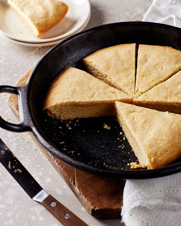 Sugar cookie cut into wedges in a skillet, one wedge served on a plate