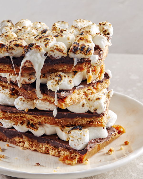 A stack of S’mores bars, with chocolate, graham crackers, and toasted marshmallows, on a white plate.