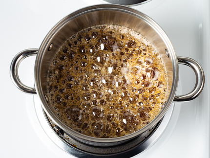 Sugar at a full boil in a pot on a stove
