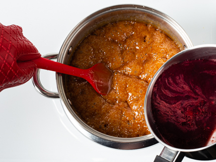 Pouring strawberry-wine sauce into a pot of boiling sugar and heavy cream