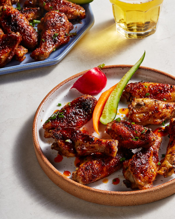 A plate of sweet and spicy grilled chicken wings served with raw vegetables