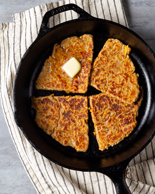 Sweet potato farls in a cast-iron skillet with a pat of butter