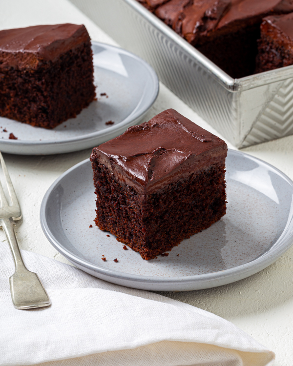 Cut squares of vegan chocolate cake with icing on plates