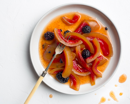 A plate of pickled watermelon rinds and blackberries with a long fork