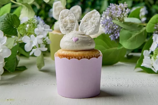 Decorative Easter-themed lemon cupcakes with buttercream frosting and coconut-dipped marshmallow bunny ears, showcased in pastel cupcake wrappers, perfect for a festive spring dessert.