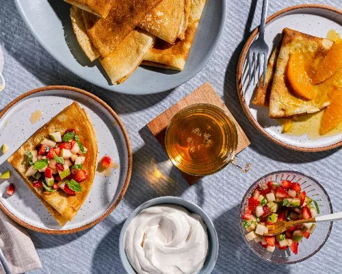 Plates of crepes with fruit toppings and brown sugar whipped sour cream