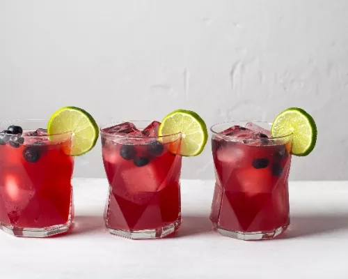 Three glasses of Blueberry Beer Cocktail garnished with blueberries and lime