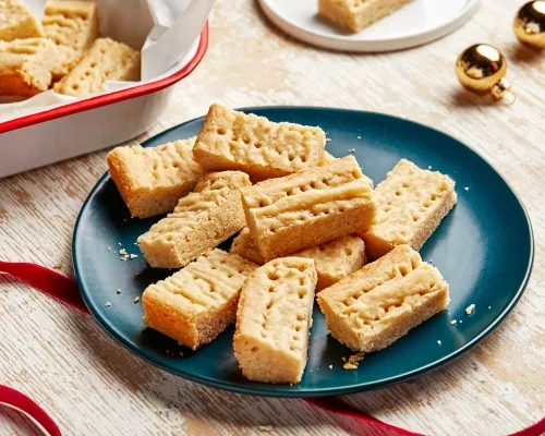 Shortbread cookies on a blue plate with red ribbons and gold Christmas ornaments