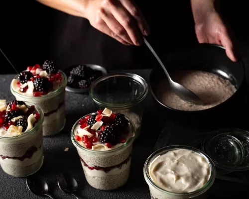 Vanilla cardamom chia pudding in a cup garnished with blackberries, coconut and pomegranate