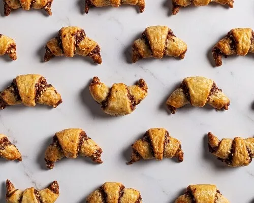 Chocolate tahini rugelach crescents arranged on a marble counter