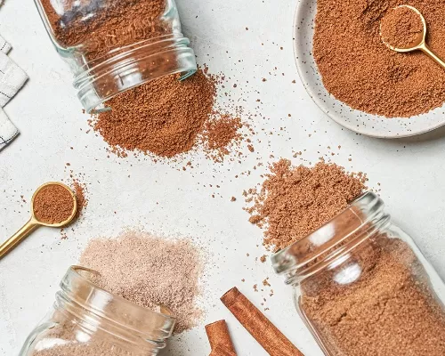 Three jars of cinnamon sugar spilled on a table