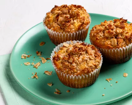 Three muffins topped with coconut streusel on a green plate