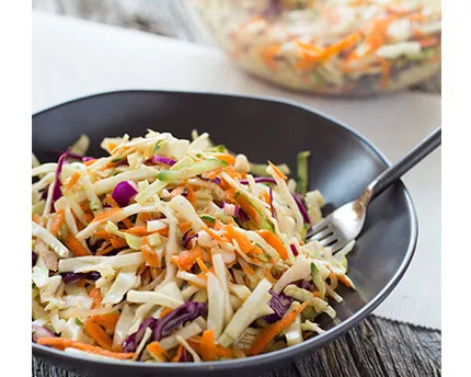 Coleslaw and Cucumber Salad in a black bowl with a fork