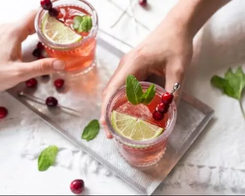 Hands grabbing Cranberry Mint Punch off a silver tray