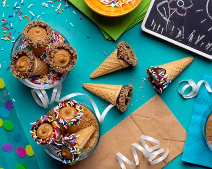 Chocolate dipped ice cream cones full of brown sugar fudge with rainbow sprinkles and party decor