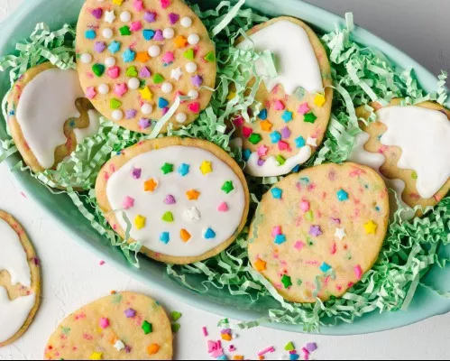 6 Easter egg cookies decorated with sprinkles and royal icing in a basket