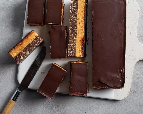 Nanaimo bar cut into slices on a cutting board