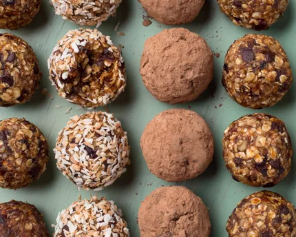 Fruit & Nut energy bites lined up on a painted wood background