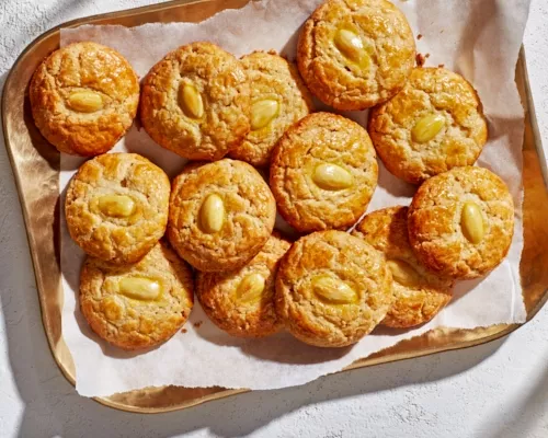 A baker’s dozen golden almond cookies on a brass tray.