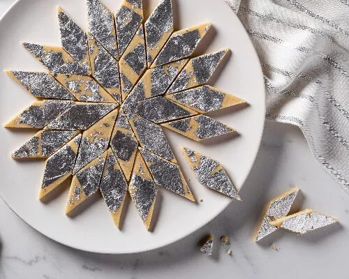 Kaju katli on a plate, cut into diamonds and decorated with silver leaf