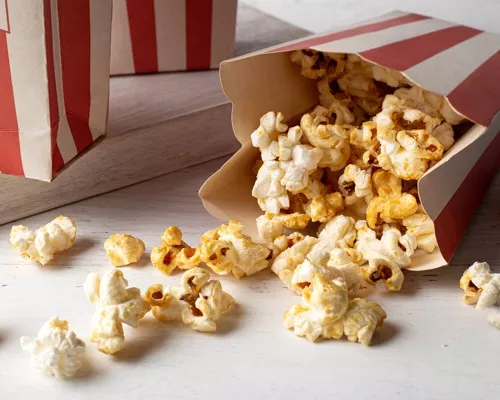 Kettle corn spilling out of a red and white striped popcorn bag