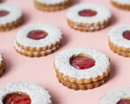 Strawberry Linzer Cookies in rows on a pink background