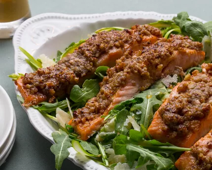Arugula salad with crusted salmon fillets in a white bowl